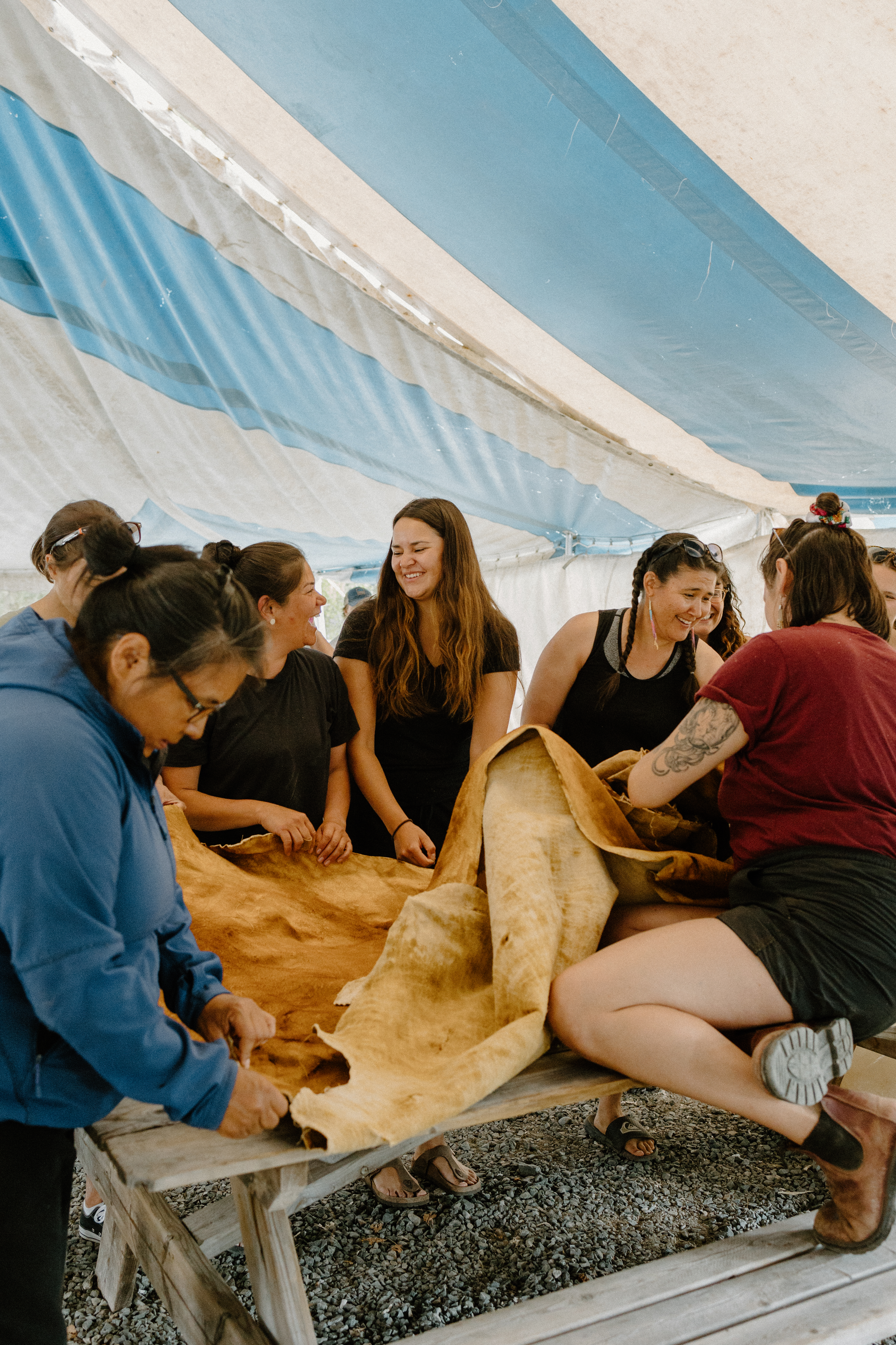 Kyla LeSage (centre) feels a finished moosehide. (Photo: Morgan Tsetta/Dechinta Centre for Learning and Research)