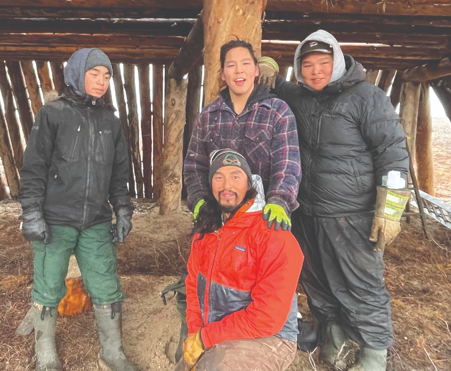 Noel Cockney and students inside Tuk's new sod house.
