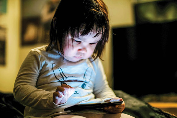 Two-year-old Sarah opens an app on a cell phone in Arviat. CREDIT PAUL ANINGAT