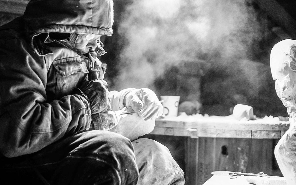 Billy Kuksuk of Arviat,  Nunavut carves a wolf outside his house in a -30 C windchill for an executive from Agnico Eagle's Meadowbank Mine. Photo by Paul Aningat