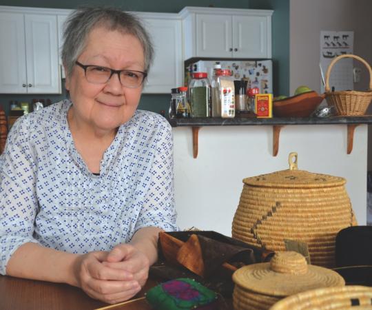 Margaret Lawrence at home in her kitchen, surrounded by some of her hand-sewn grass baskets. 